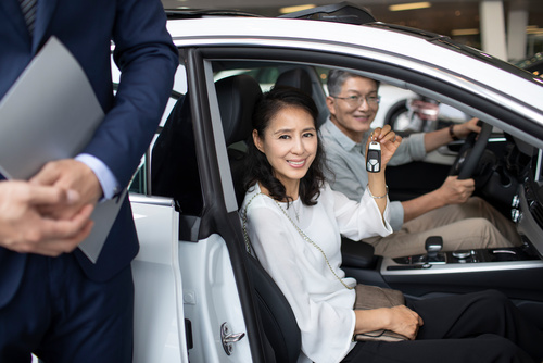 Happy mature couple buying car in showroom